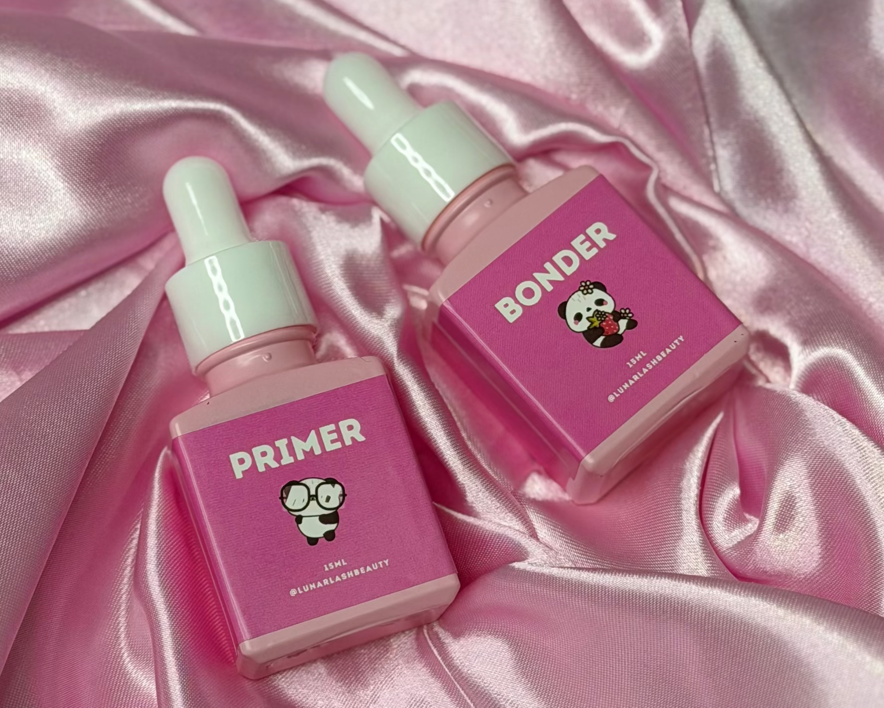 Two pink bottles labeled 'Primer' and 'Bonder' on a pink satin background